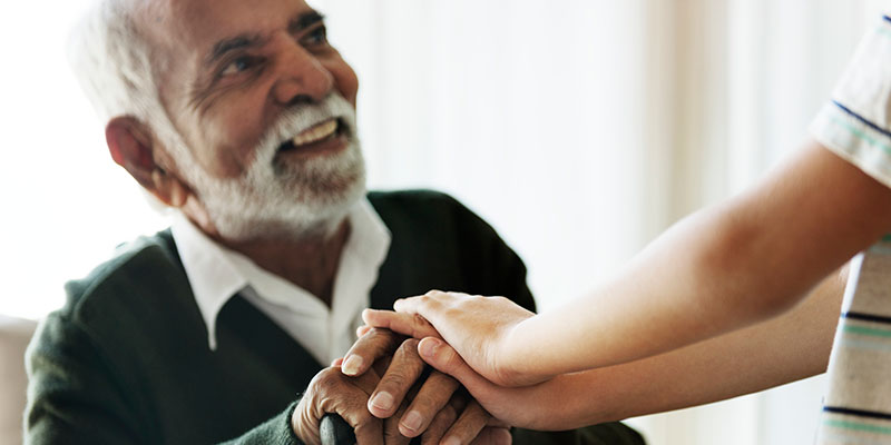 elderly man with younger hands at The Delaney at Lake Waco senior living