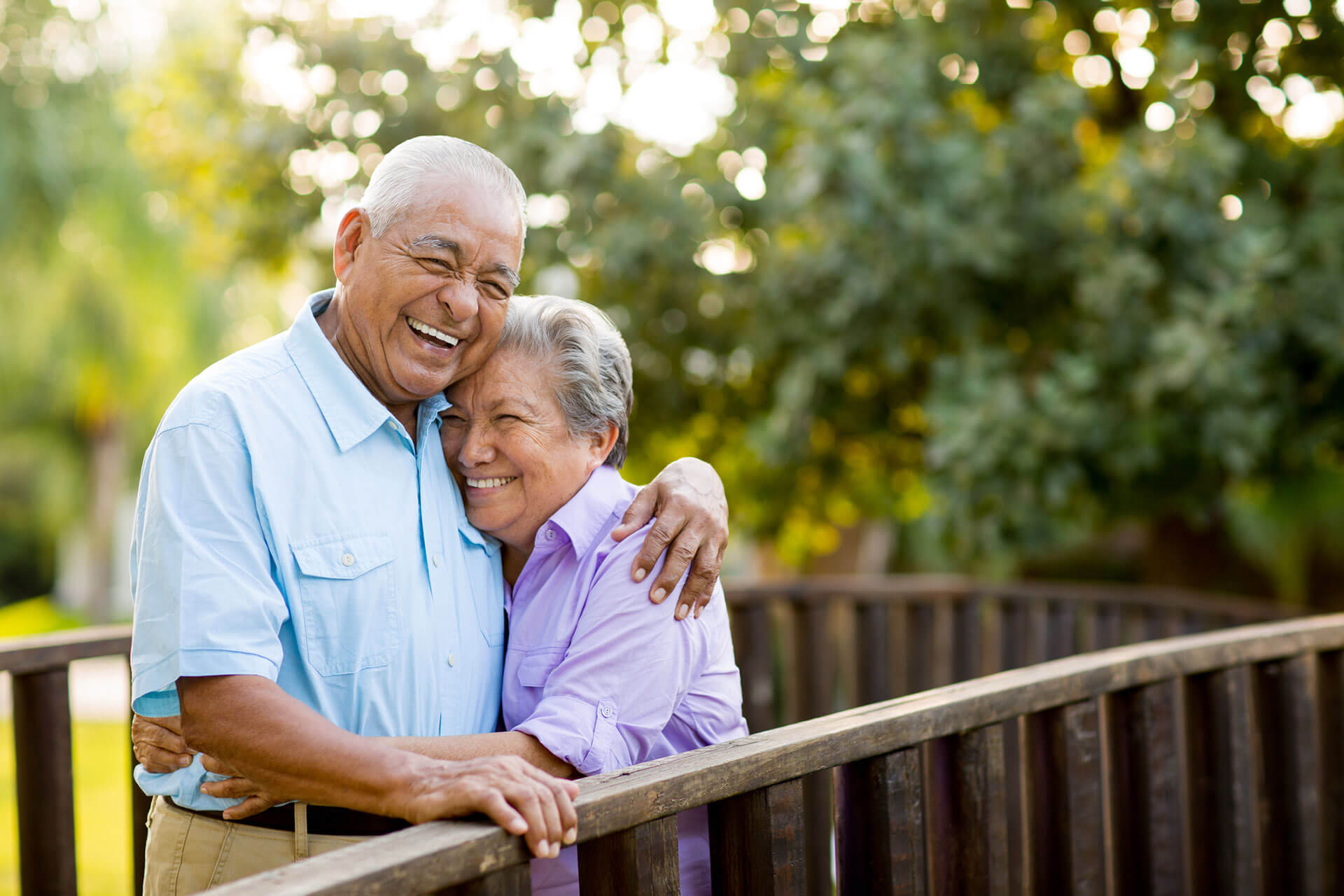 elderly couple hugging on a deck at The Delaney at Lake Waco senior living community