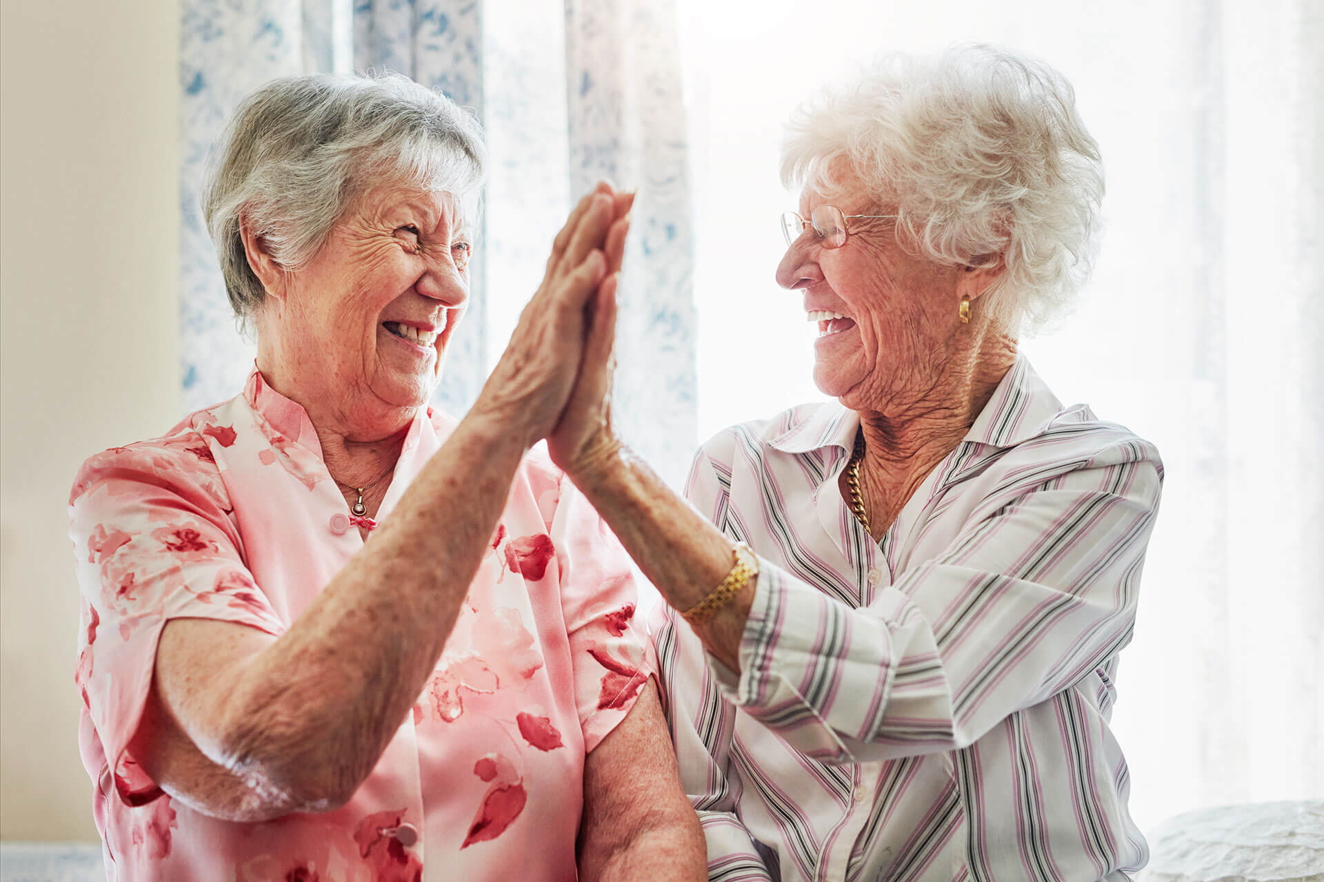 elderly women doing a high-five at The Delaney at Lake Waco senior living retirement community