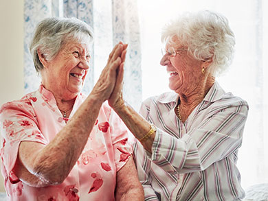 elderly women doing a high-five at The Delaney at Lake Waco senior living retirement community