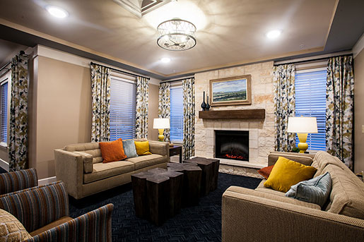 Cozy living room with sofas, a fireplace, and decorative accents in a communal area.