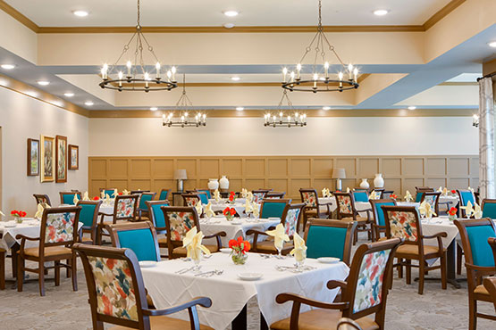 Elegant dining area with chandeliers and colorful chairs in a spacious room.