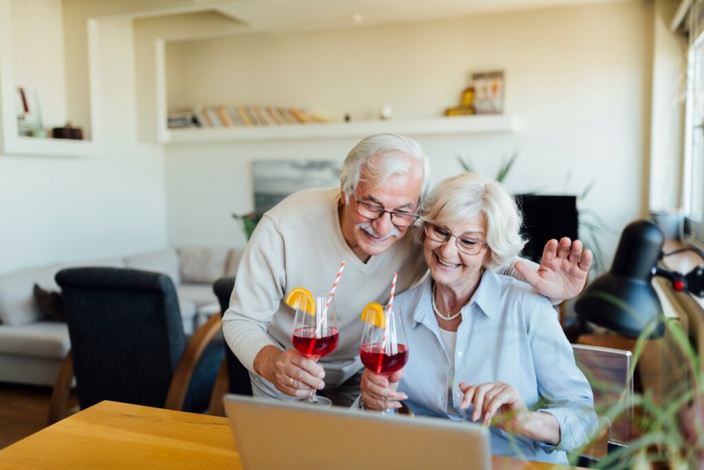 elderly couple with cocktails watching laptop