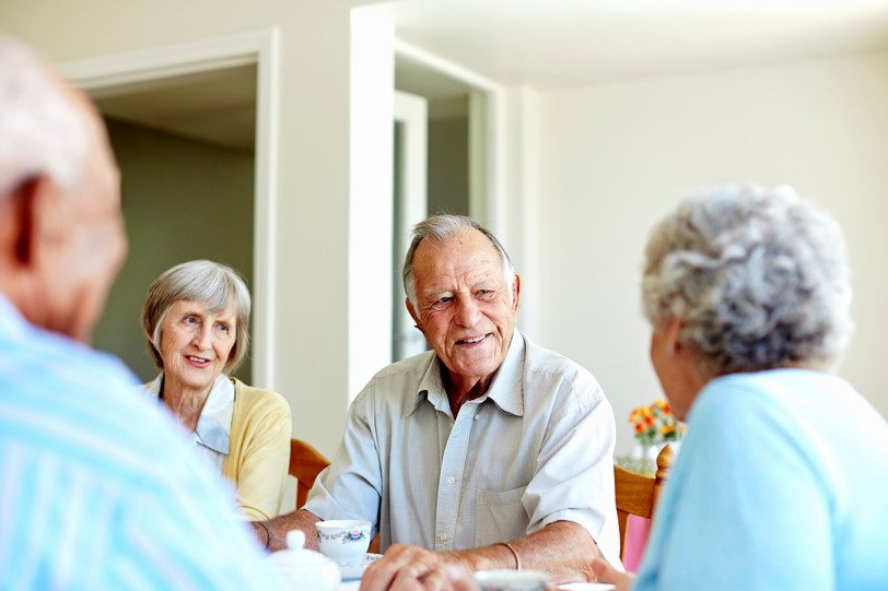 Group of seniors conversing at a table with a bright, inviting atmosphere.