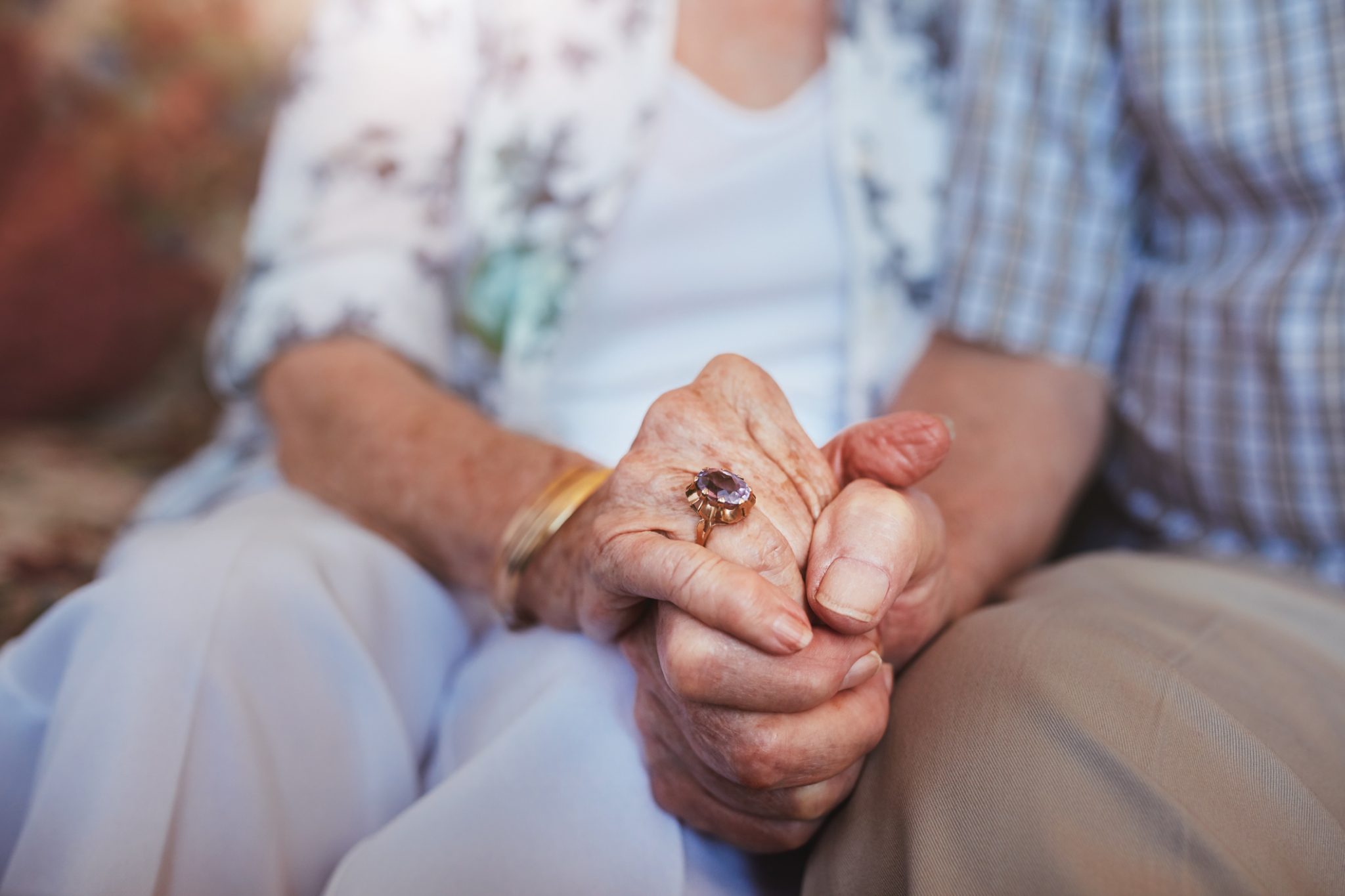 Close-up of elderly couple holding hands, showing a deep connection and support.